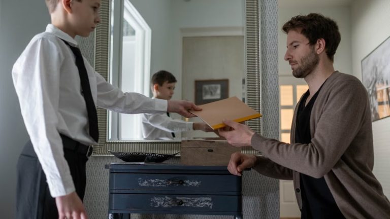 A father and son exchanging an envelope in an indoor setting, reflecting parenthood and communication.